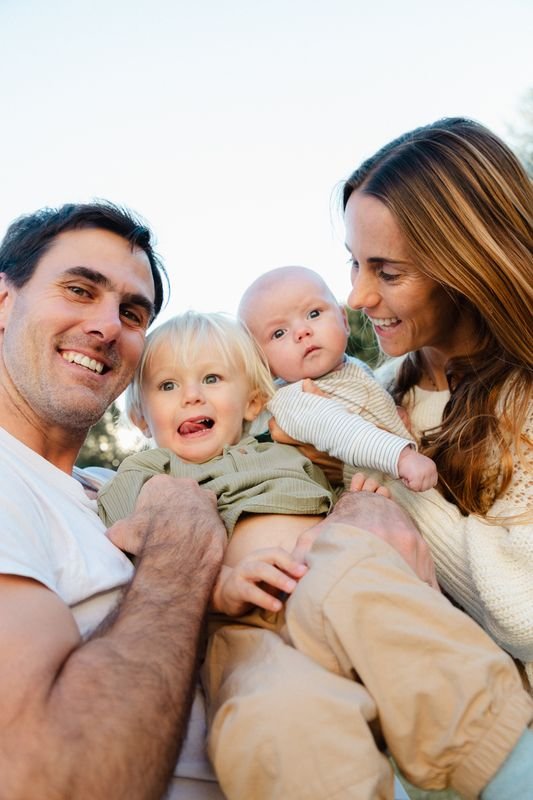 Familia de cuatro abrazada al aire libre