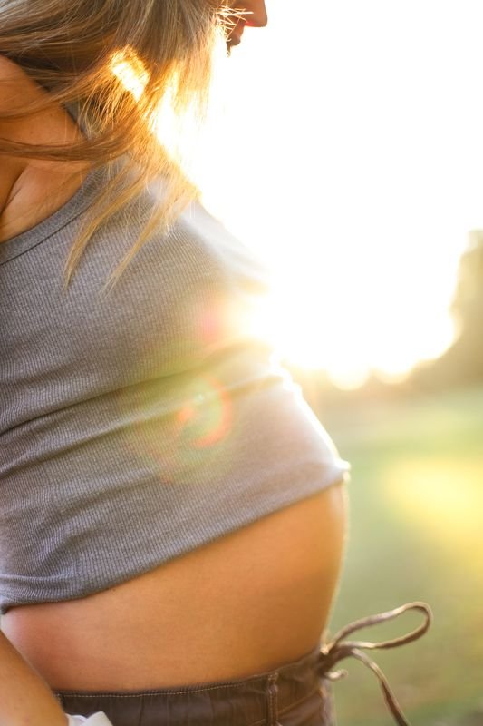 Embarazada tocándose la panza al sol